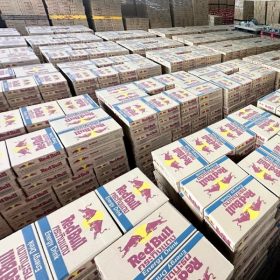 Pallets of Red Bull 250ml cans in a wholesale market setting, illustrating global distribution.