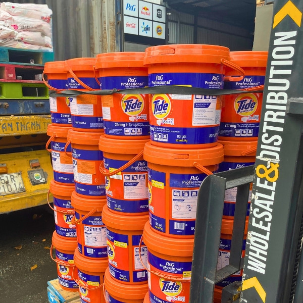 Multiple buckets of Tide with Downy detergent stacked for wholesale distribution beside a forklift.